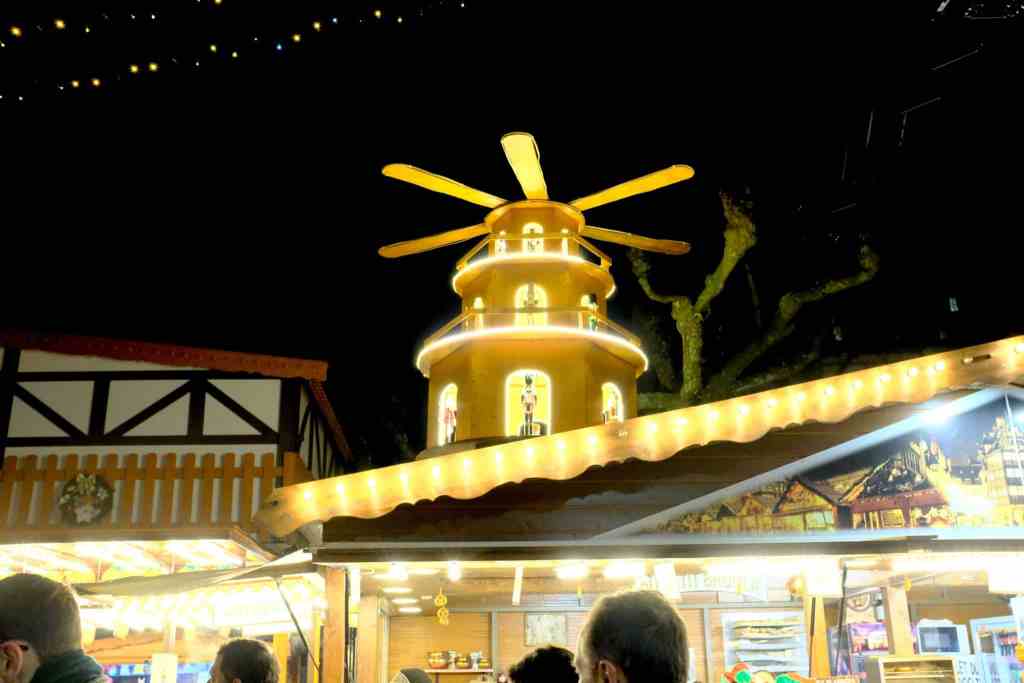 Une pyramide de Noël illuminée au marché, avec des figurines visibles à travers les fenêtres, tournée par la chaleur des bougies.